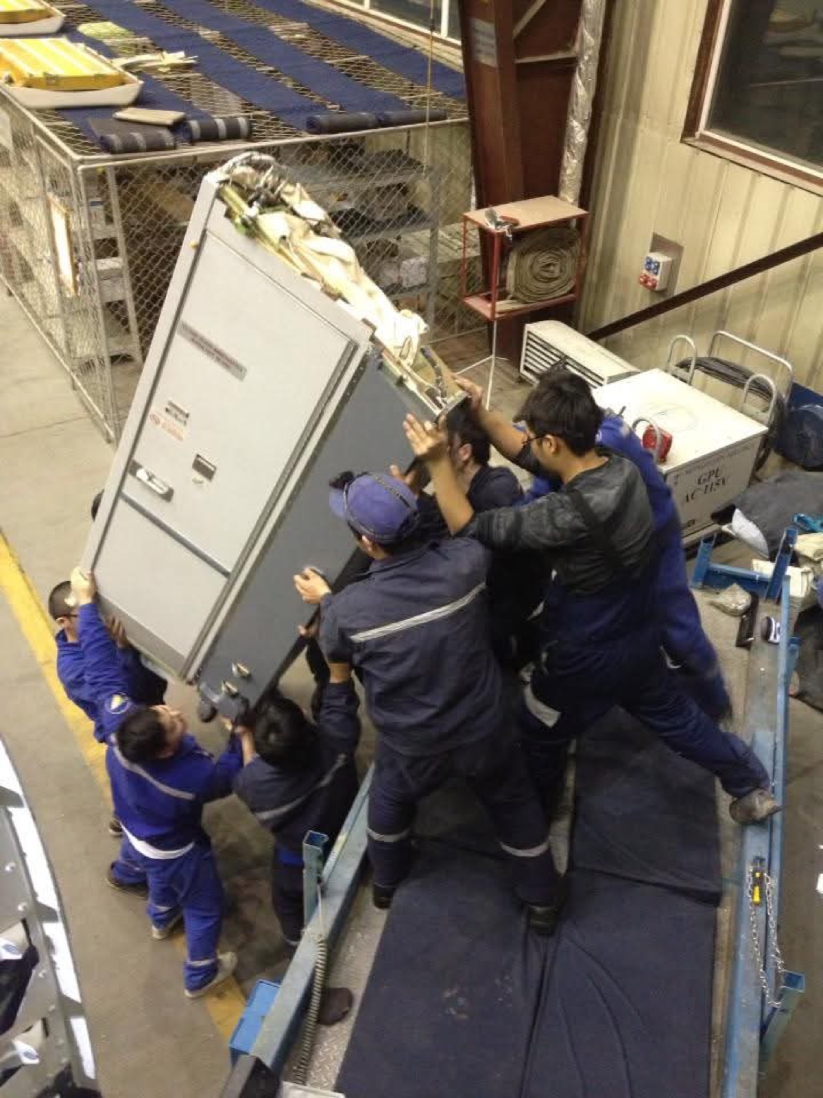 Team moving aircraft equipment in a hangar